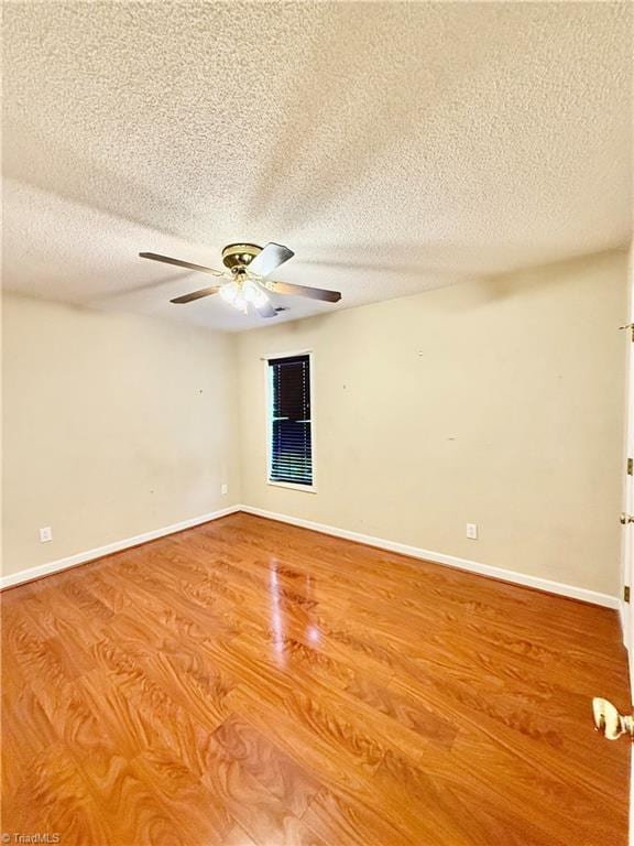 empty room with ceiling fan, wood-type flooring, and a textured ceiling