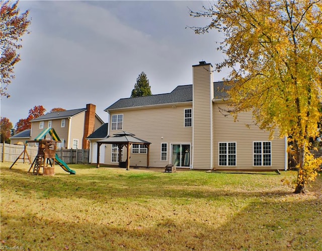 rear view of property featuring a gazebo, a yard, and a playground