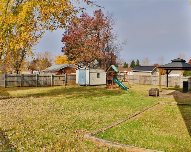 view of yard featuring a gazebo, a storage unit, a fire pit, and a playground