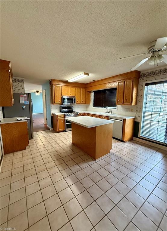 kitchen featuring ceiling fan, a kitchen island, light tile patterned floors, and appliances with stainless steel finishes