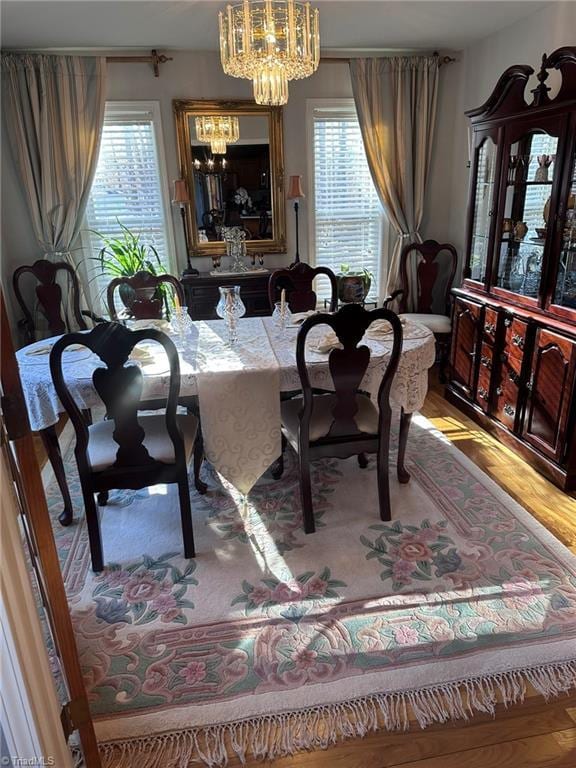 dining area with hardwood / wood-style floors, a wealth of natural light, and a notable chandelier