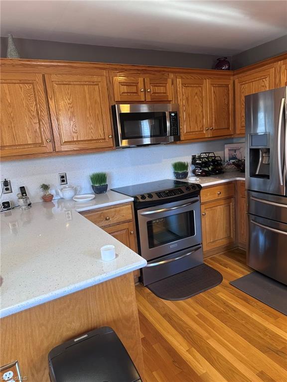 kitchen featuring stainless steel appliances, light stone counters, and light hardwood / wood-style floors