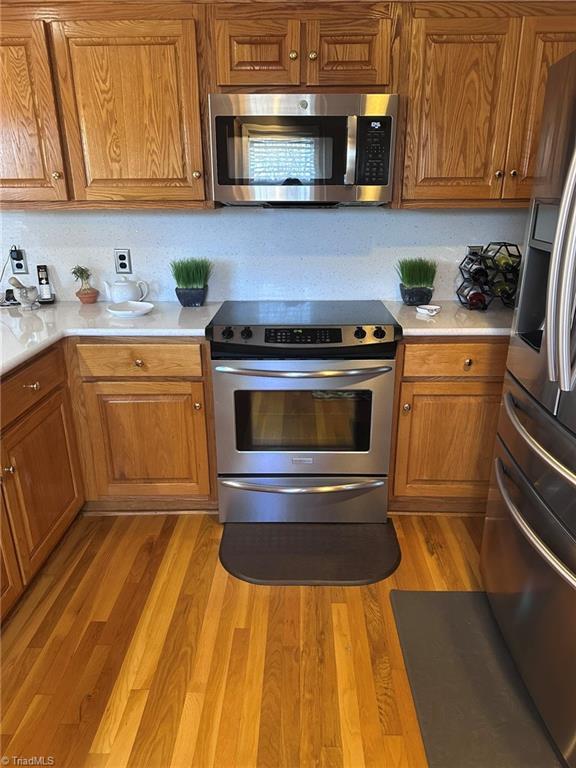 kitchen with appliances with stainless steel finishes and light hardwood / wood-style flooring