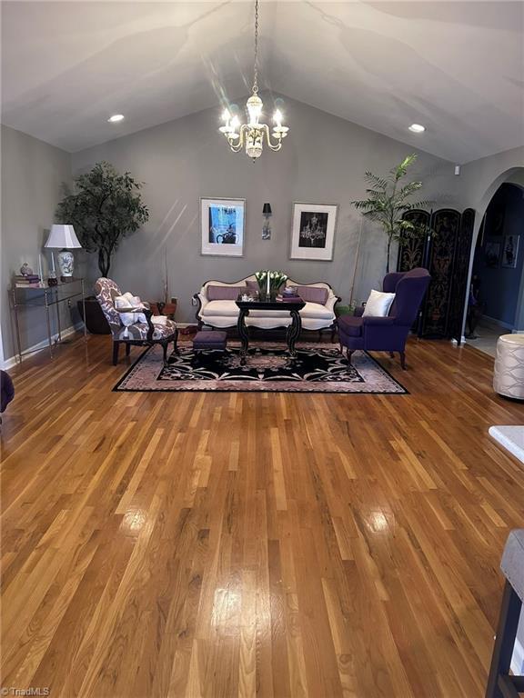 dining space featuring hardwood / wood-style flooring, a notable chandelier, and vaulted ceiling