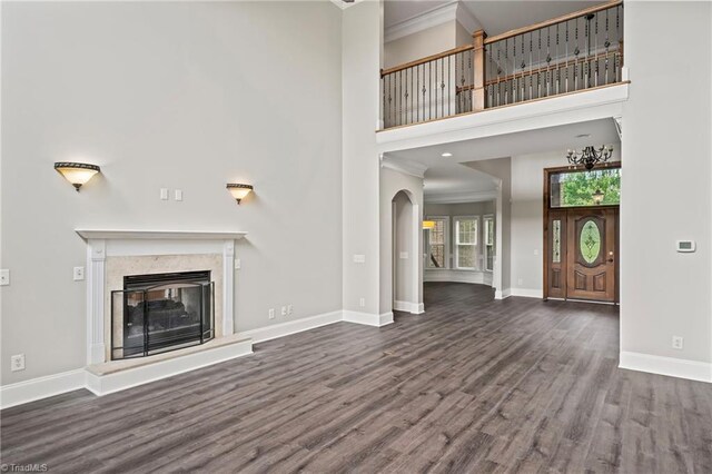 unfurnished living room with a high ceiling, ornamental molding, and dark hardwood / wood-style flooring