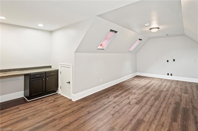 additional living space with dark hardwood / wood-style flooring and lofted ceiling with skylight