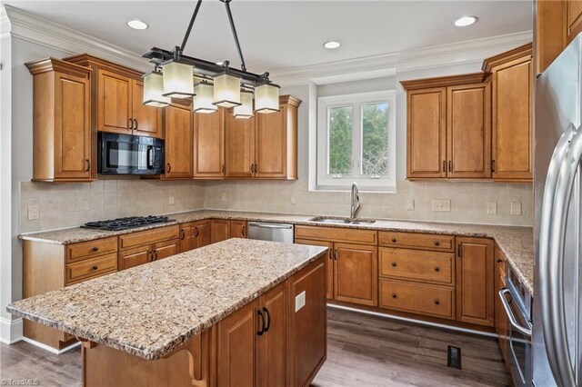 kitchen featuring a breakfast bar area, dark wood-type flooring, decorative light fixtures, sink, and stainless steel appliances