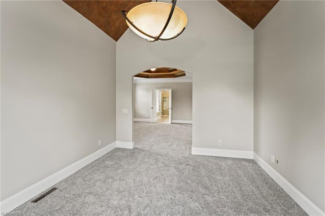 empty room with carpet flooring, lofted ceiling, and ornamental molding