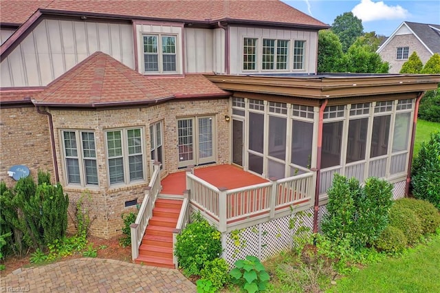 rear view of house featuring a sunroom, a patio area, and a deck