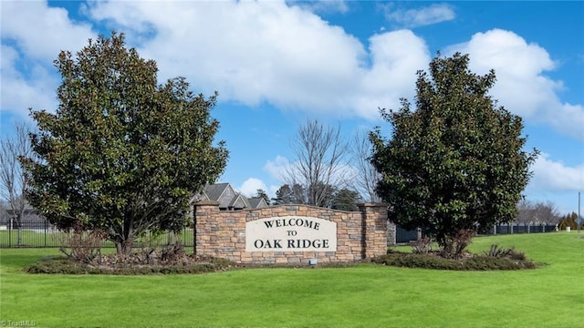 community sign featuring a lawn and fence
