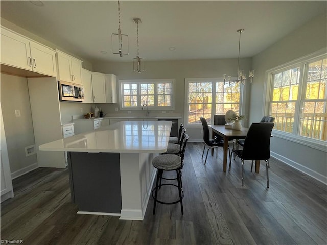 kitchen with dark wood finished floors, stainless steel microwave, a wealth of natural light, and a center island