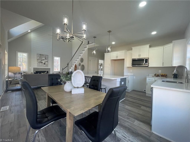 dining space with stairway, dark wood finished floors, recessed lighting, a fireplace, and a chandelier