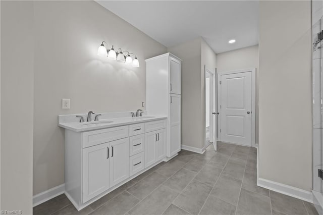 full bathroom with double vanity, baseboards, and a sink