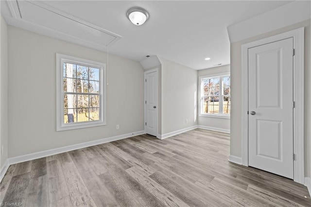 unfurnished bedroom with attic access, wood finished floors, and baseboards