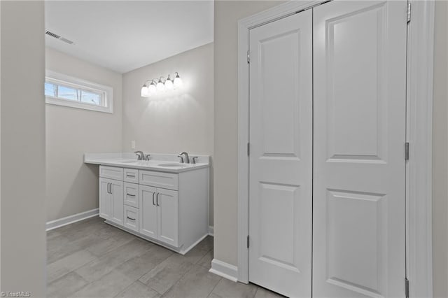 full bathroom with a sink, visible vents, baseboards, and double vanity