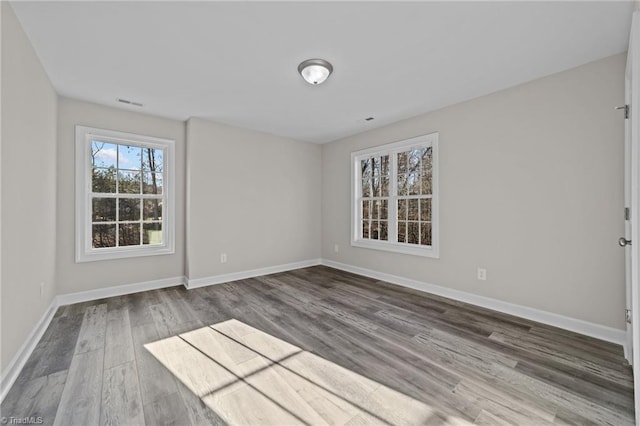 unfurnished room featuring visible vents, baseboards, and wood finished floors