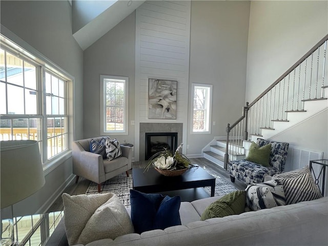 living area featuring a fireplace, stairs, a towering ceiling, and wood finished floors