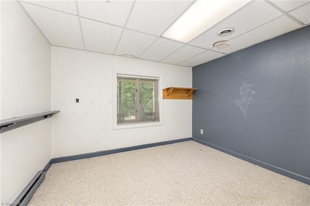 carpeted empty room with a paneled ceiling, baseboards, and a baseboard radiator