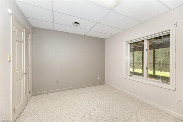 carpeted spare room with a paneled ceiling and baseboards