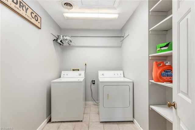 laundry room featuring washing machine and clothes dryer, baseboards, and light tile patterned flooring