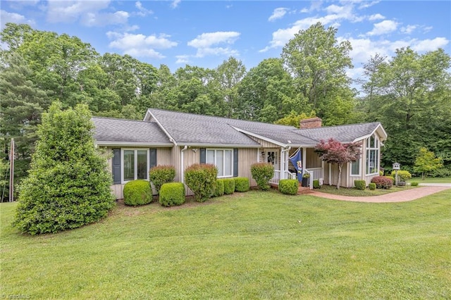 single story home featuring a chimney, a front yard, and a porch