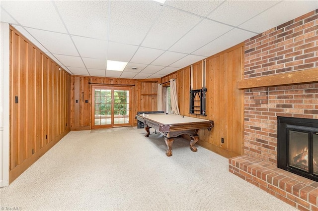 rec room featuring wooden walls, carpet floors, a brick fireplace, billiards, and a paneled ceiling