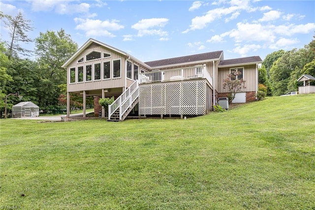 rear view of property with a greenhouse, stairway, a sunroom, an outdoor structure, and a lawn