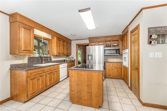 kitchen with stainless steel appliances, a sink, a kitchen island, backsplash, and ornamental molding