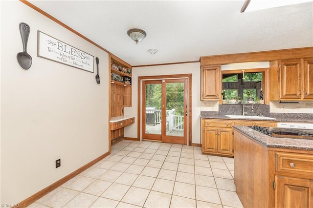kitchen featuring a sink, ornamental molding, decorative backsplash, baseboards, and brown cabinetry