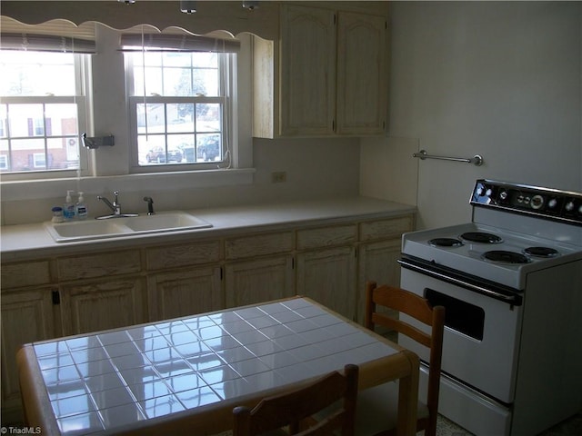 kitchen featuring sink, light brown cabinets, white range with electric stovetop, and tile counters