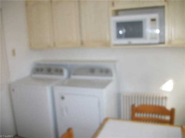 washroom with cabinets, washing machine and dryer, and radiator