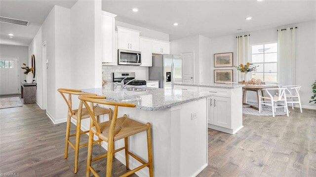 445 Tobacco Rd, Lexington, NC 27295 - kitchen featuring stainless steel appliances, wood finished floors, a peninsula, a breakfast bar area, and a kitchen island