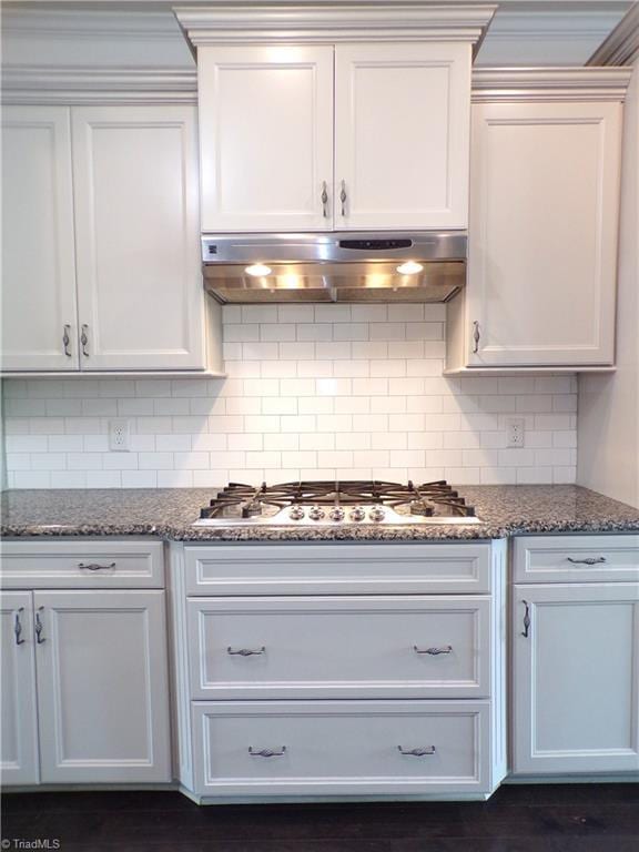 8003 Helison Ct, Stokesdale, NC 27357 - kitchen with under cabinet range hood, tasteful backsplash, stainless steel gas cooktop, dark stone counters, and crown molding