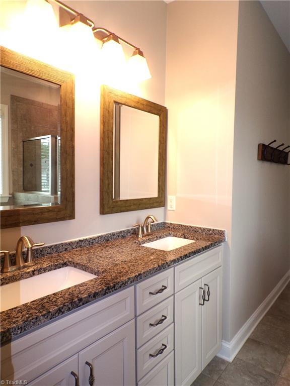 8003 Helison Ct, Stokesdale, NC 27357 - full bathroom with baseboards, tiled shower, double vanity, and a sink