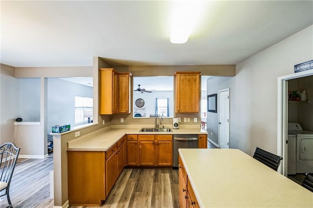 kitchen with washer and dryer, dishwasher, wood-type flooring, and sink