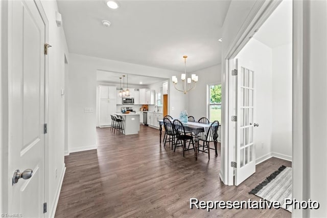 dining area featuring dark wood finished floors, a notable chandelier, and baseboards