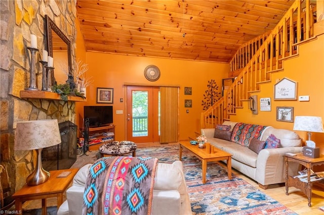 living room featuring wood ceiling, lofted ceiling, light hardwood / wood-style floors, and a stone fireplace