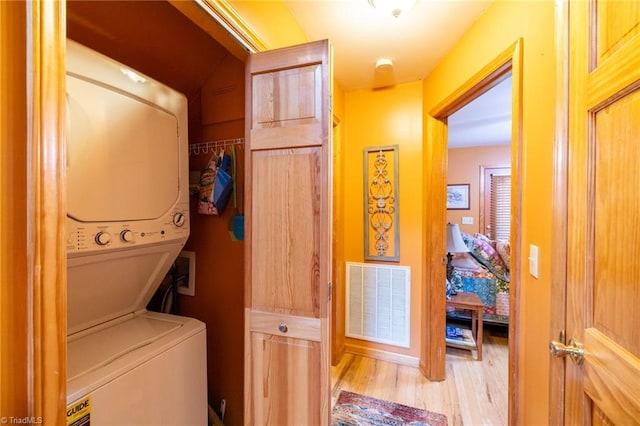 washroom featuring light hardwood / wood-style floors and stacked washer and dryer