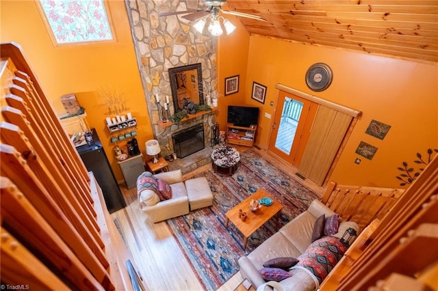 living room featuring ceiling fan, a stone fireplace, hardwood / wood-style floors, and high vaulted ceiling