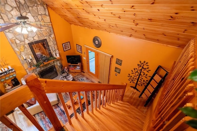 staircase featuring wood ceiling, ceiling fan, high vaulted ceiling, and a stone fireplace