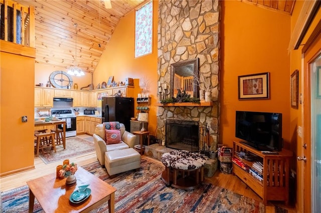 living room with light wood-type flooring, wood ceiling, a fireplace, and high vaulted ceiling