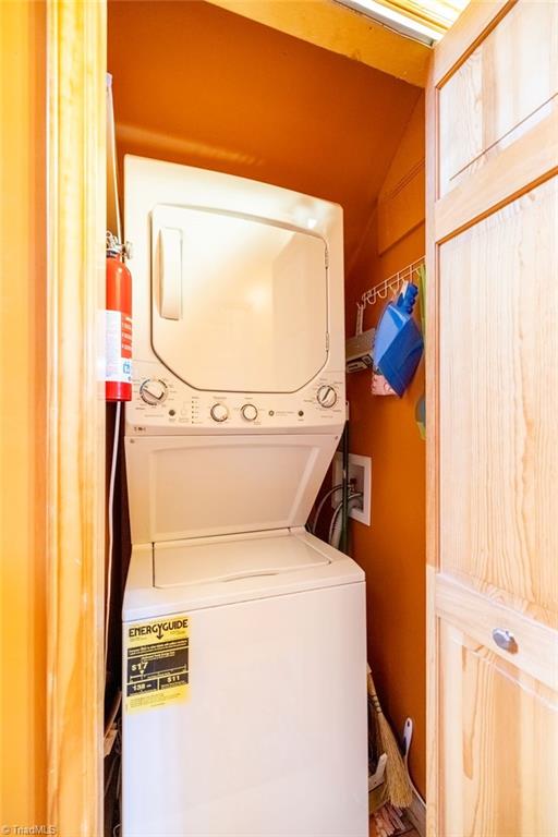 clothes washing area featuring stacked washing maching and dryer