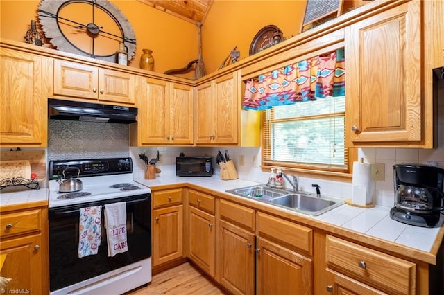 kitchen with backsplash, lofted ceiling, tile counters, sink, and electric range