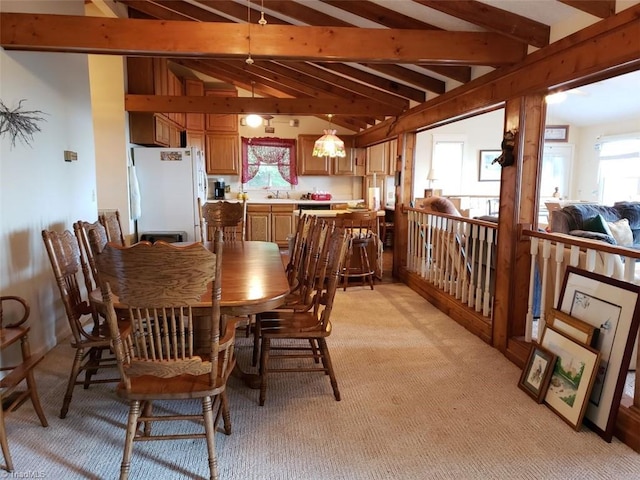 dining area with sink, light colored carpet, and lofted ceiling with beams