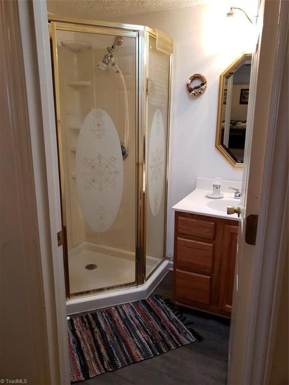 bathroom with vanity, wood-type flooring, a textured ceiling, and walk in shower