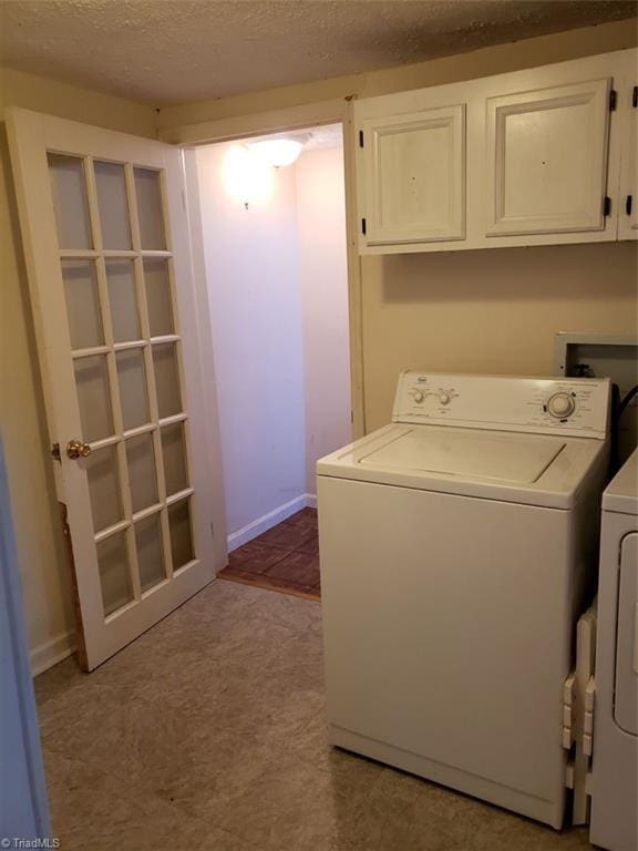 clothes washing area featuring cabinets, a textured ceiling, and washing machine and dryer