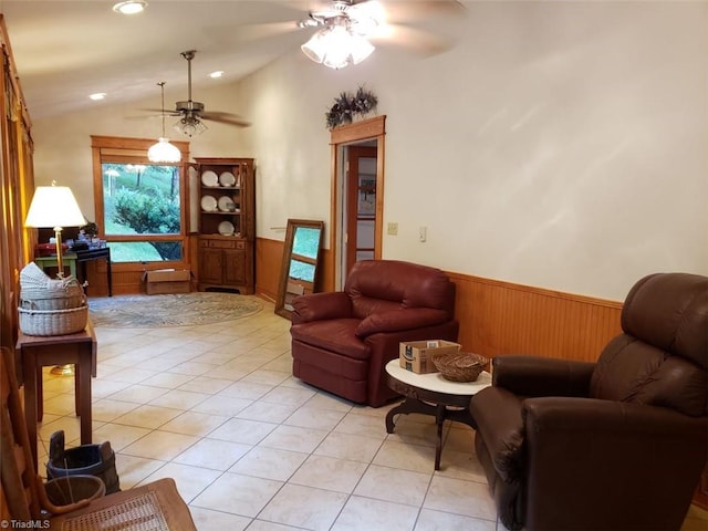 tiled living room featuring ceiling fan, wooden walls, and vaulted ceiling