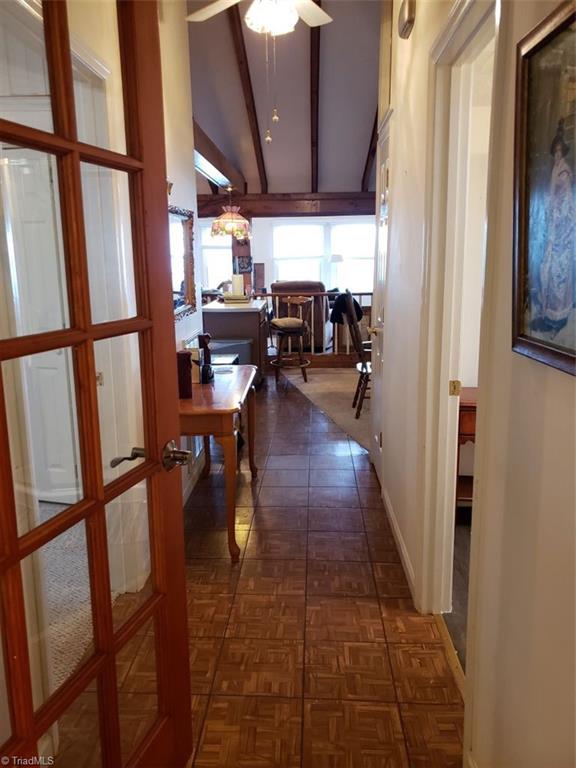 hall with dark parquet flooring, french doors, and lofted ceiling with beams