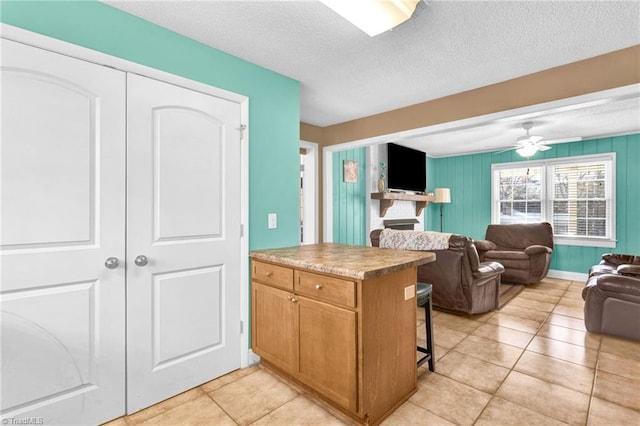 kitchen featuring ceiling fan, a kitchen breakfast bar, kitchen peninsula, a textured ceiling, and light tile patterned flooring