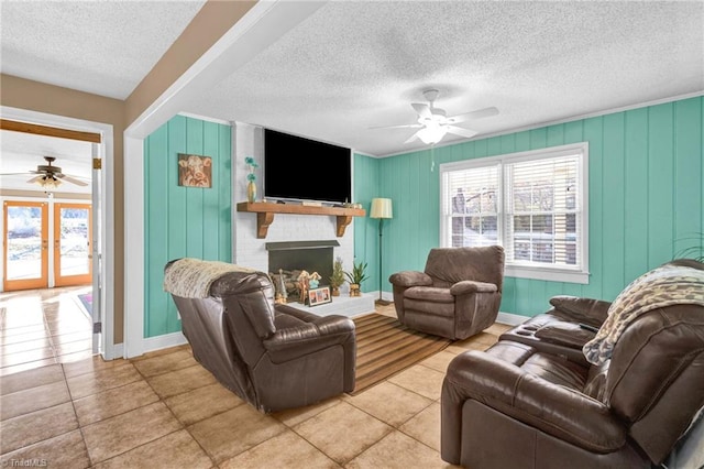 living room featuring ceiling fan, light tile patterned floors, a textured ceiling, and a brick fireplace